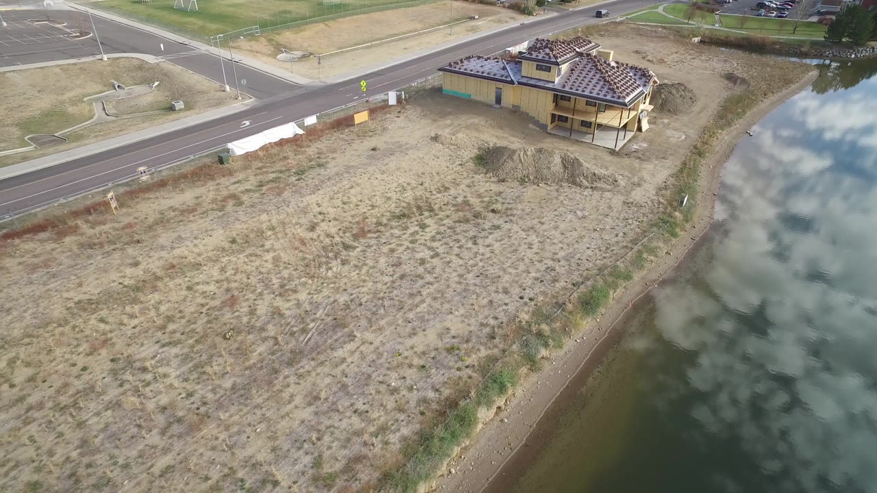 High aerial view in Hidden Lake, Colorado with the lake along the right side, dry grassland across the center, a road at the top, and no visible people.