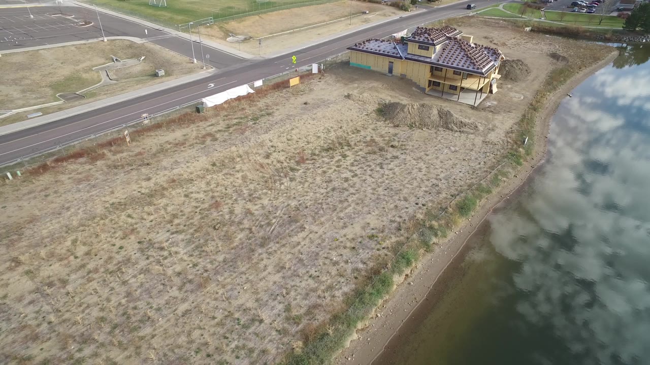 Aerial view of lakeside lot with house and road above it.