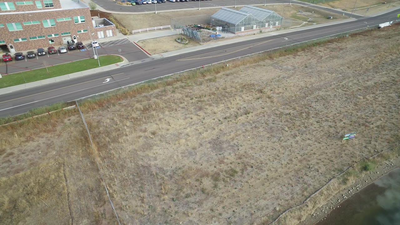 Drone-like view over dry land with road and buildings across the top