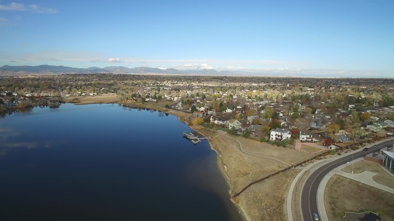 Lakefront neighborhood aerial with road curve at lower right and mountains beyond.