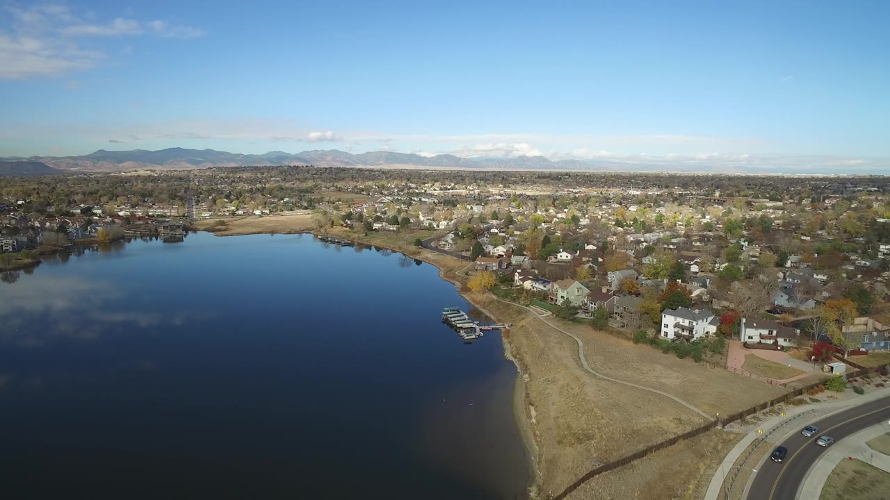 Early aerial view of Hidden Lake, Colorado, showing the lake surface on the left, shoreline houses and docks near center, a road at the lower right, and no visible people.