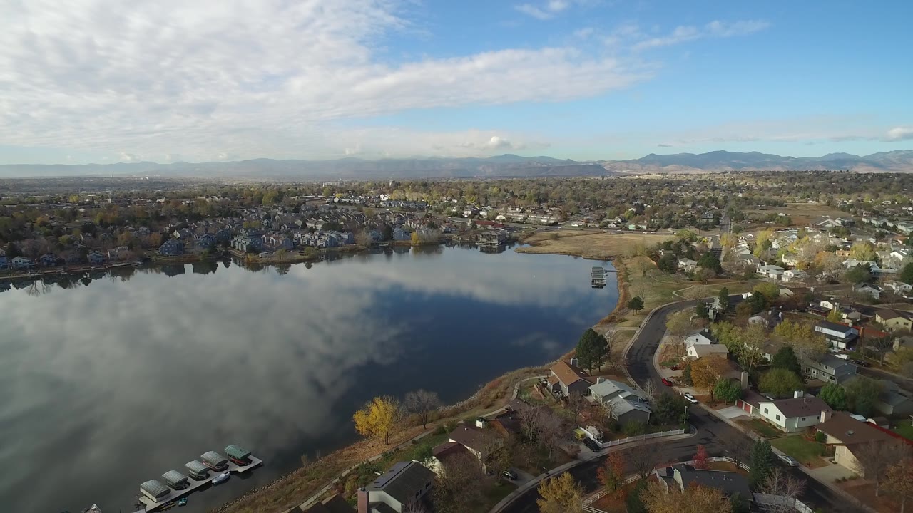 Hidden Lake, Colorado appears from above with the water filling the foreground, houses and trees around the shoreline, mountains across the horizon, and no visible people.