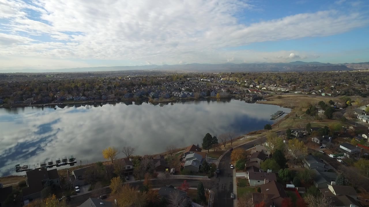 Aerial view of a lake beside homes under a cloudy sky.