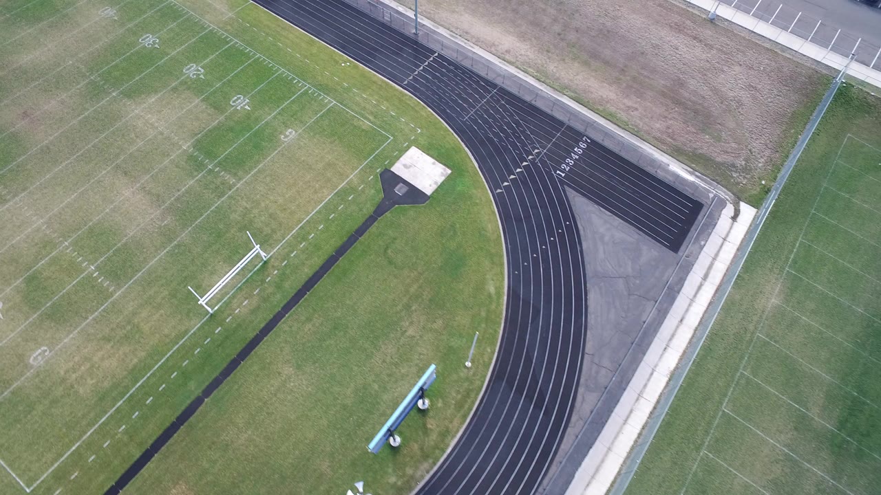 Overhead view of a football field beside a black running track.