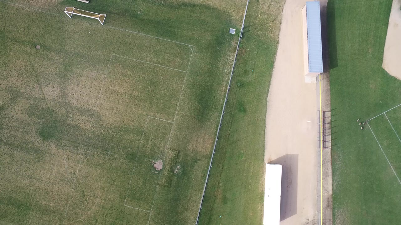 Top-down aerial frame of a mowed recreation field in Hidden Lake, Colorado, with faint sports lines, a goal near the top edge, a fence, and no visible people.