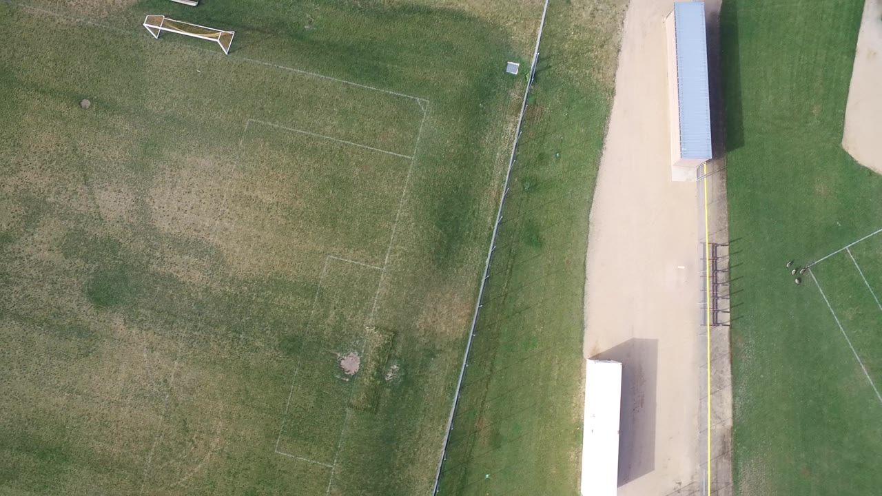 Aerial view over the Hidden Lake, Colorado field with worn rectangular markings, a goal near the upper left, fencing along the right, and no visible people.