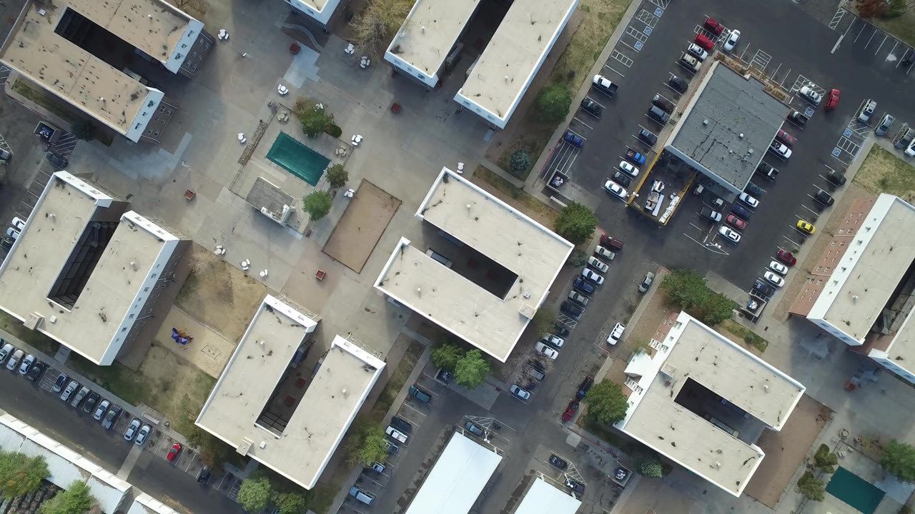 Top-down aerial view of flat-roofed buildings and parking areas.