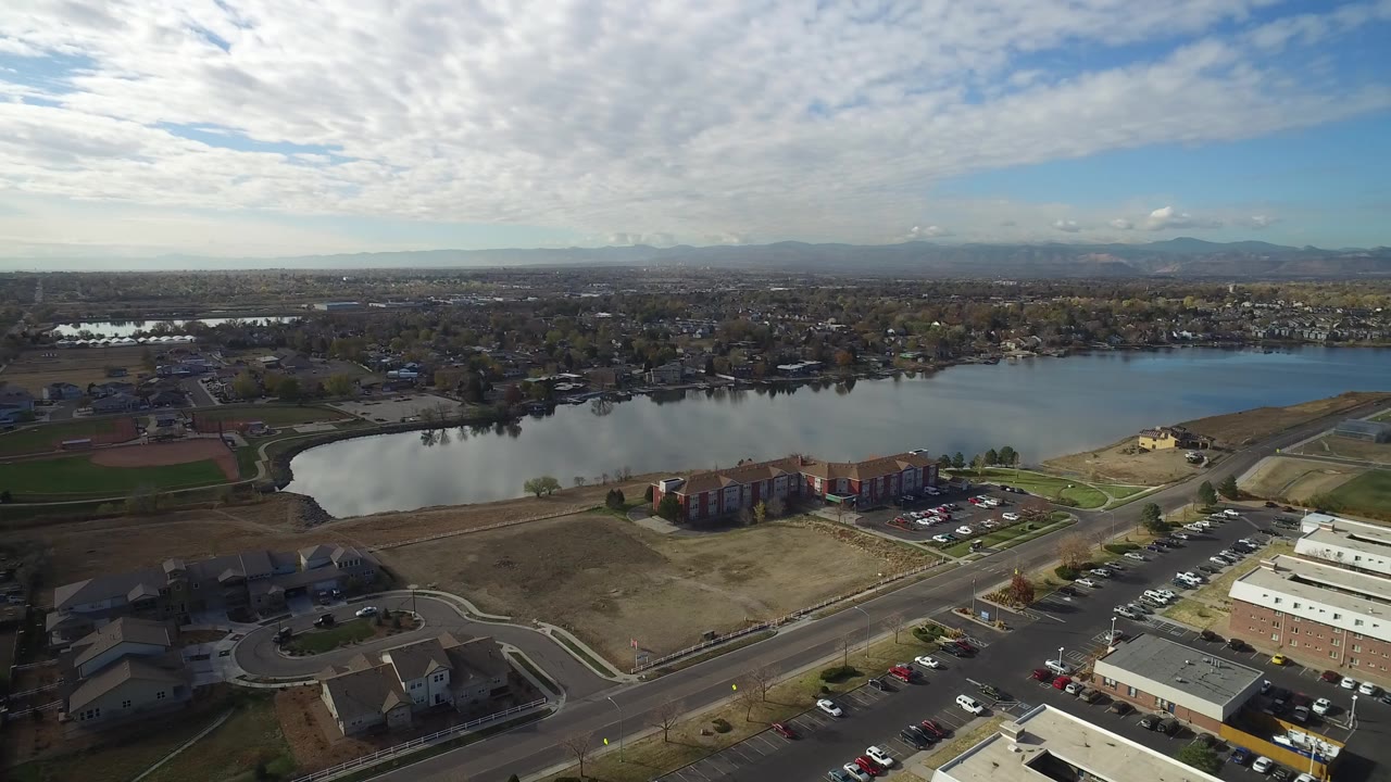 Aerial view over a lake, roads, buildings, cars, and distant mountains.