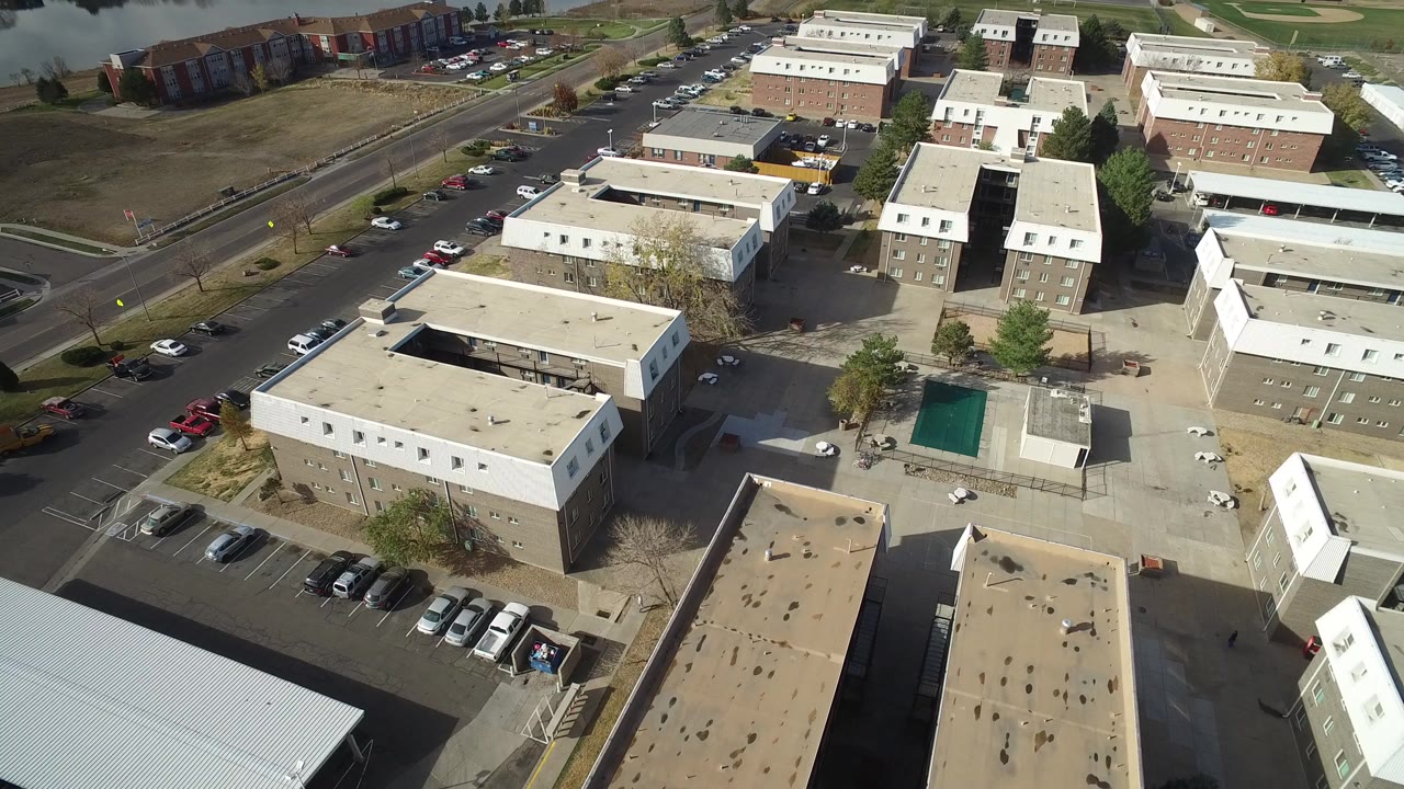 Aerial view of tan and white residential buildings with parked cars