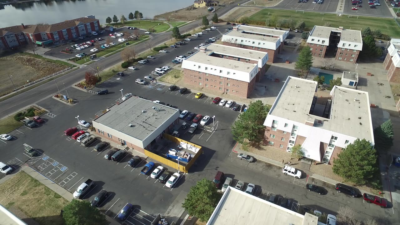 Aerial view of low-rise buildings and parking lots near water.