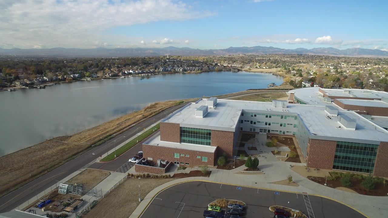 Aerial view of a brick and glass building beside a lake.