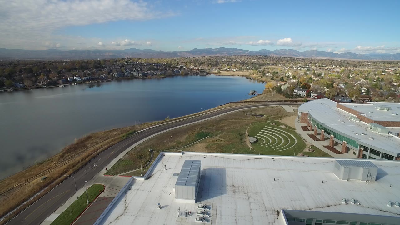 Aerial view of a lake, highway, office buildings, homes, and distant mountains.