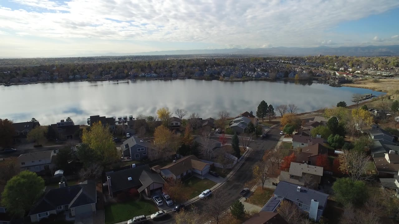 Residential rooftops and autumn trees overlooking a calm lake