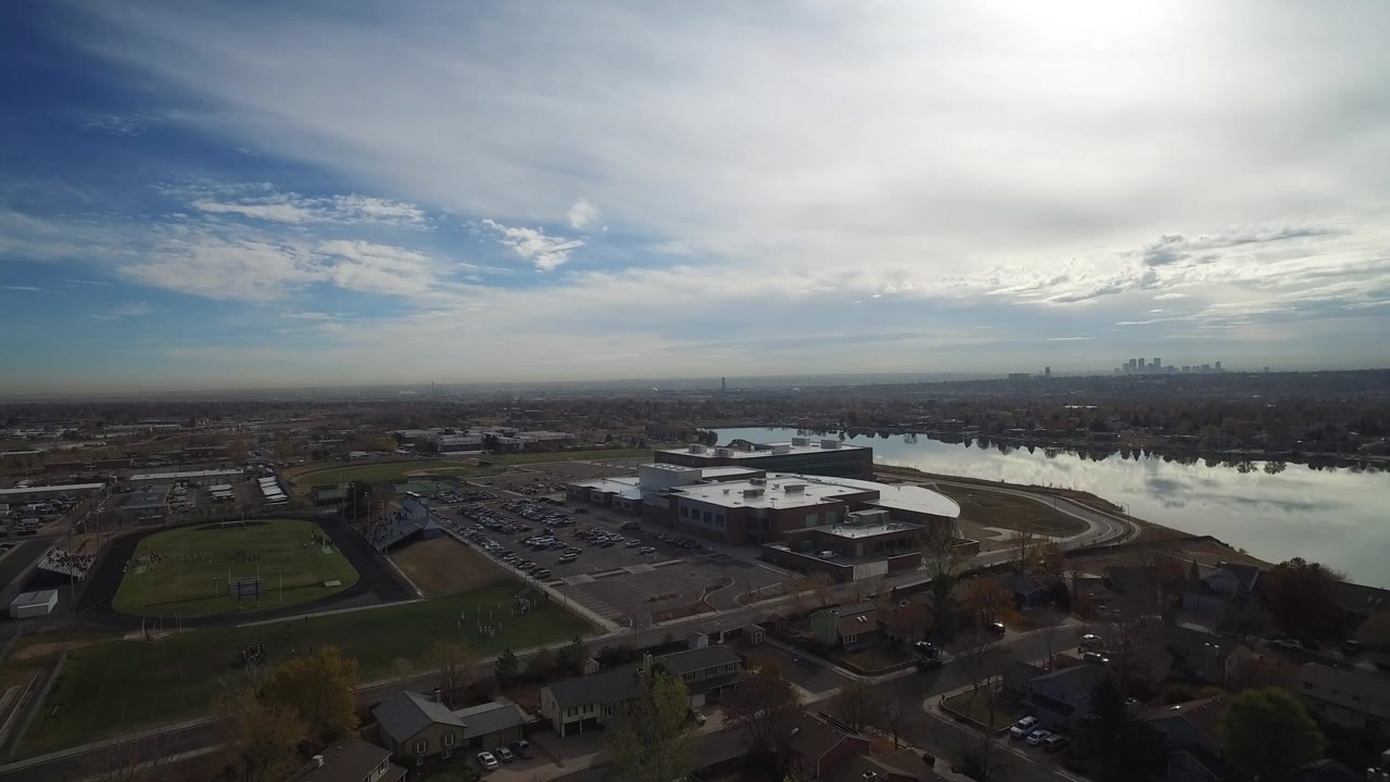 Aerial view of a lake beside suburban streets under a cloudy sky.