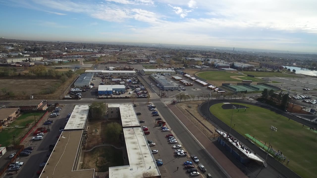 Overhead view of buildings, parking, roads, and a track field.