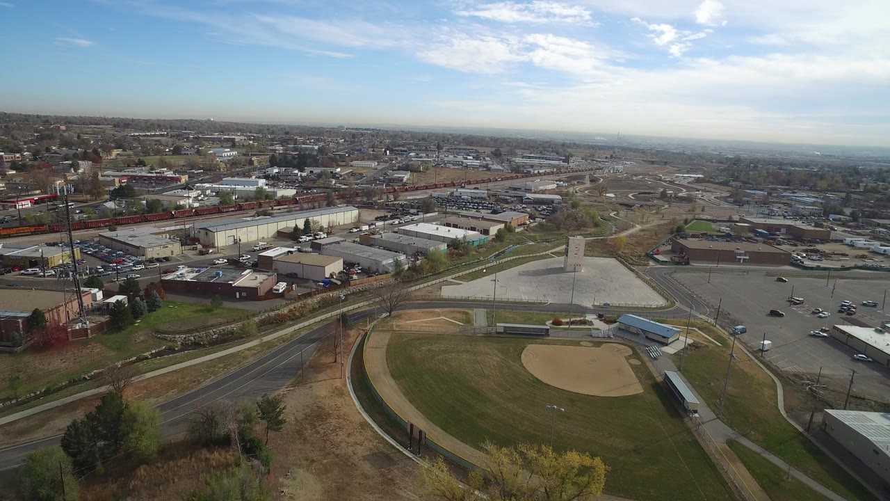 Aerial view of a baseball field beside roads and low buildings.