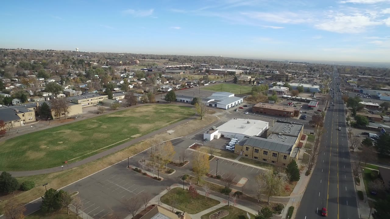 Aerial view of a field, parking lot, warehouses, and a straight avenue.