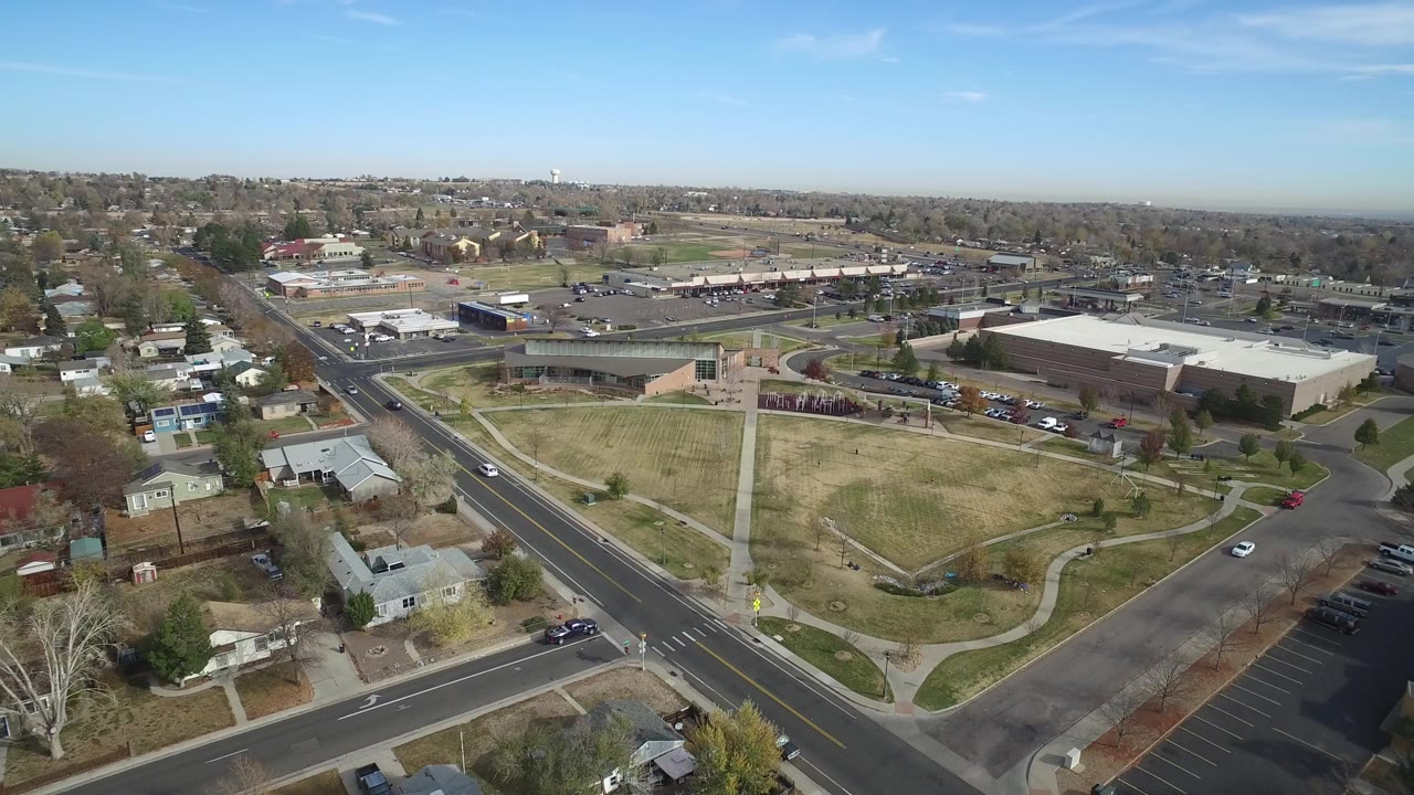 High aerial view of roads, homes, a grassy open area, and commercial buildings.