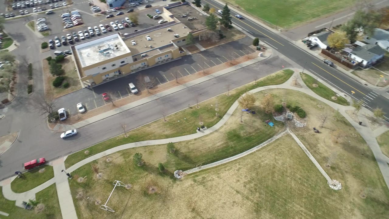 Aerial frame in Hidden Lake, Colorado with the parking lot centered, a road running along the right side, homes at the upper edge, and no visible people.