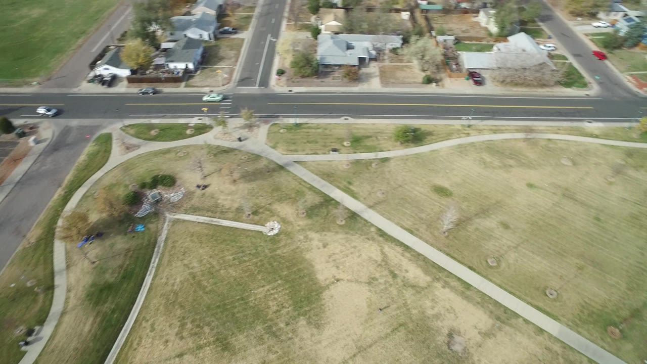 High drone-like view in Hidden Lake, Colorado, with crisscrossing sidewalks through grass, a road and houses along the top, and playground equipment near the lower left.