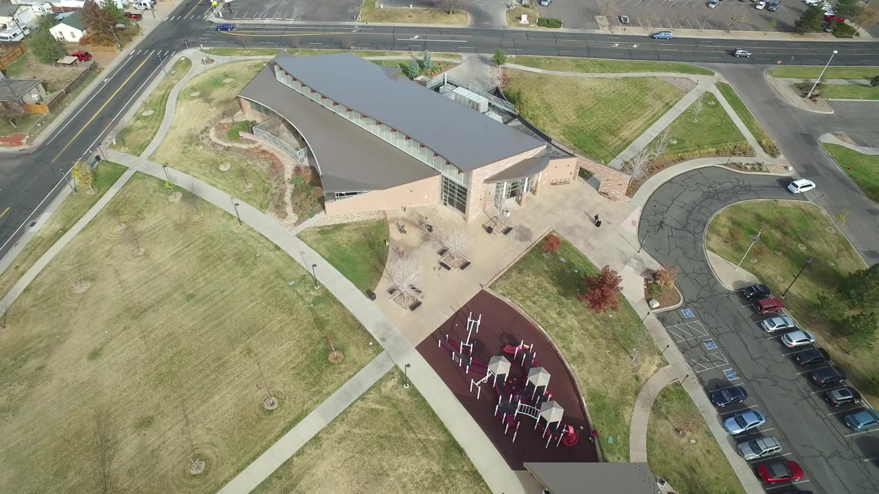 At 0:01, the Hidden Lake, Colorado aerial keeps the building near center while showing intersecting sidewalks, lawn, a curved drive, roadside lanes, and parked cars, with no visible people.