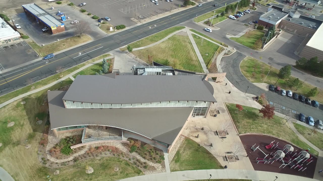 Aerial view of a campus building, playground, roads, parking, and lawn.