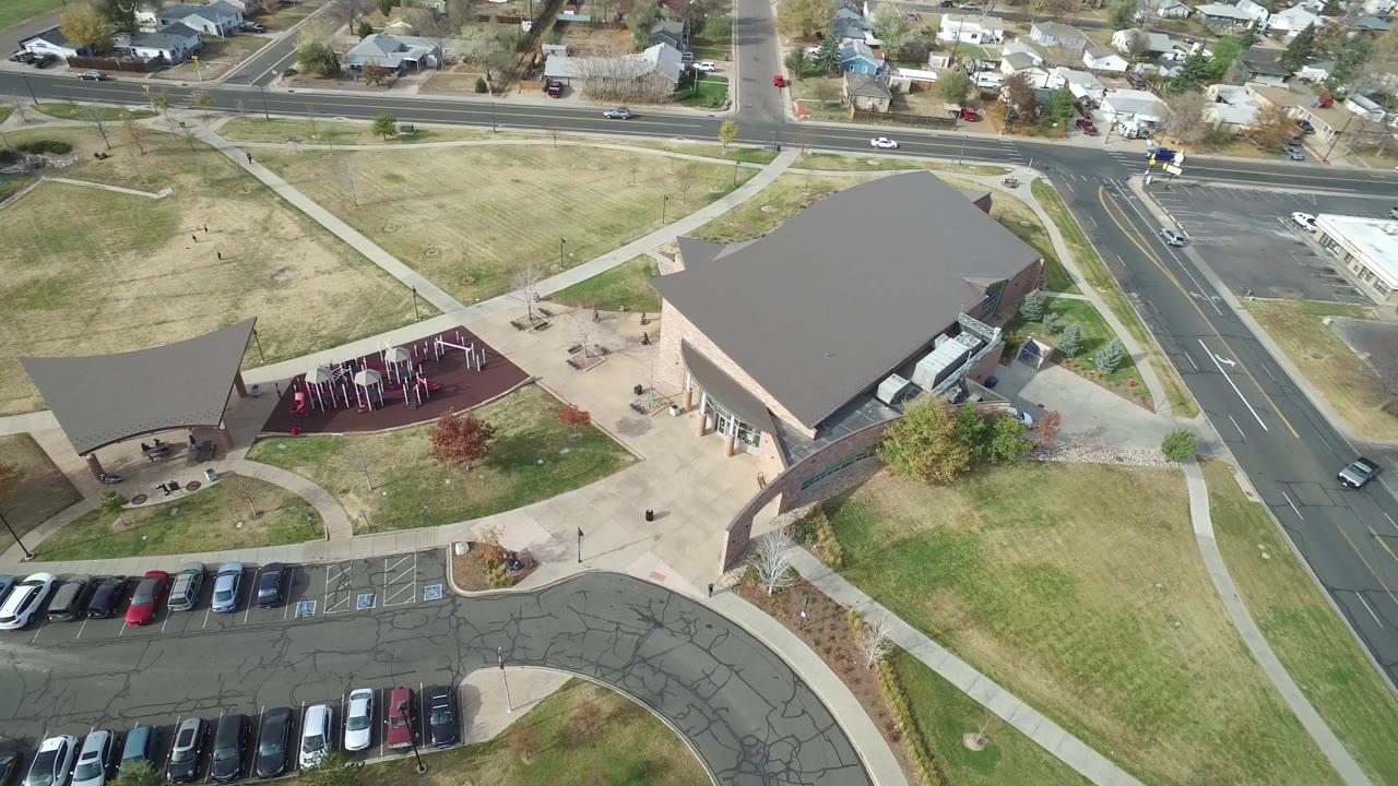 High view in Hidden Lake, Colorado with the building roof on the right, playground and pavilion on the left, a road intersection at upper right, parked cars below, and no visible people.