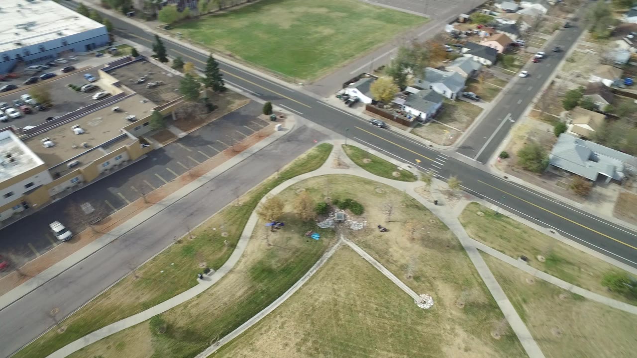 Aerial frame over Hidden Lake, Colorado showing a road intersection, park paths, grass, nearby homes, and parked cars, with no visible people.