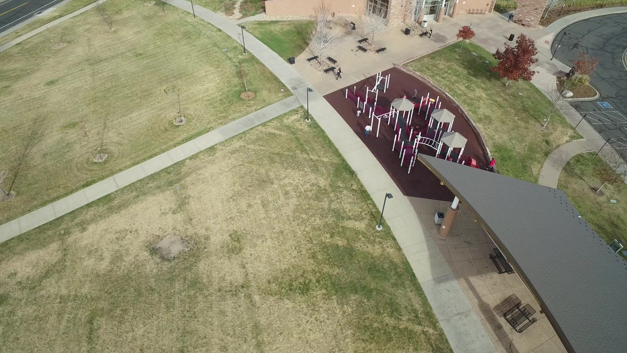 Overhead view of a playground beside lawns and a pavilion roof.