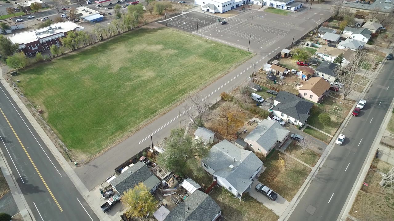 High-angle aerial view of homes beside a green field and road
