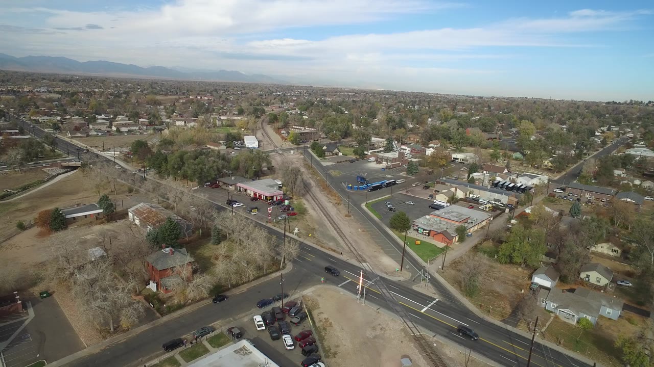 Aerial frame over Hidden Lake, Colorado centered on two roads converging beside parking lots, small buildings, residential houses, bare trees, and no visible people.