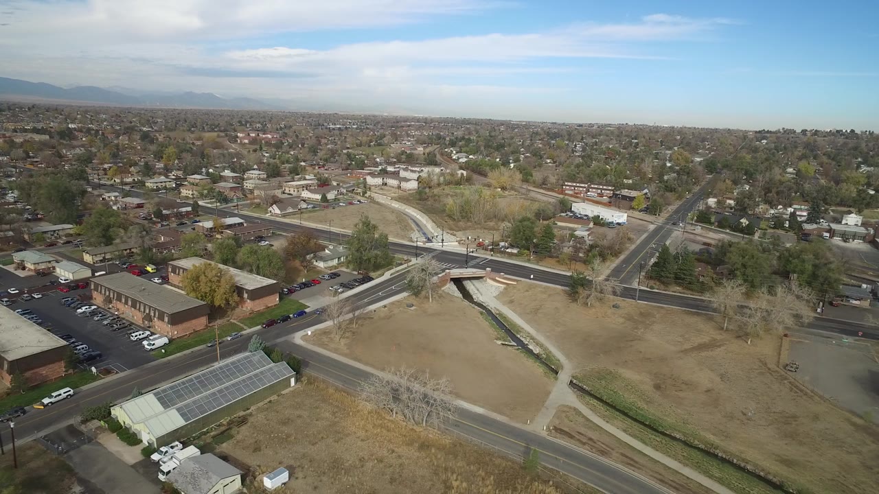 Aerial view over roads, brick commercial buildings, parking lots, and nearby homes.