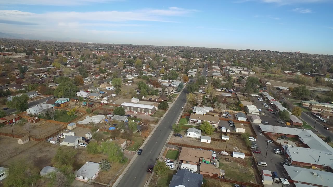 Aerial view over a residential town with a straight road and scattered houses.
