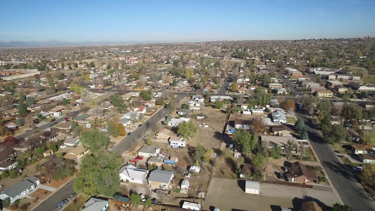Aerial view over residential streets and houses under a clear sky.