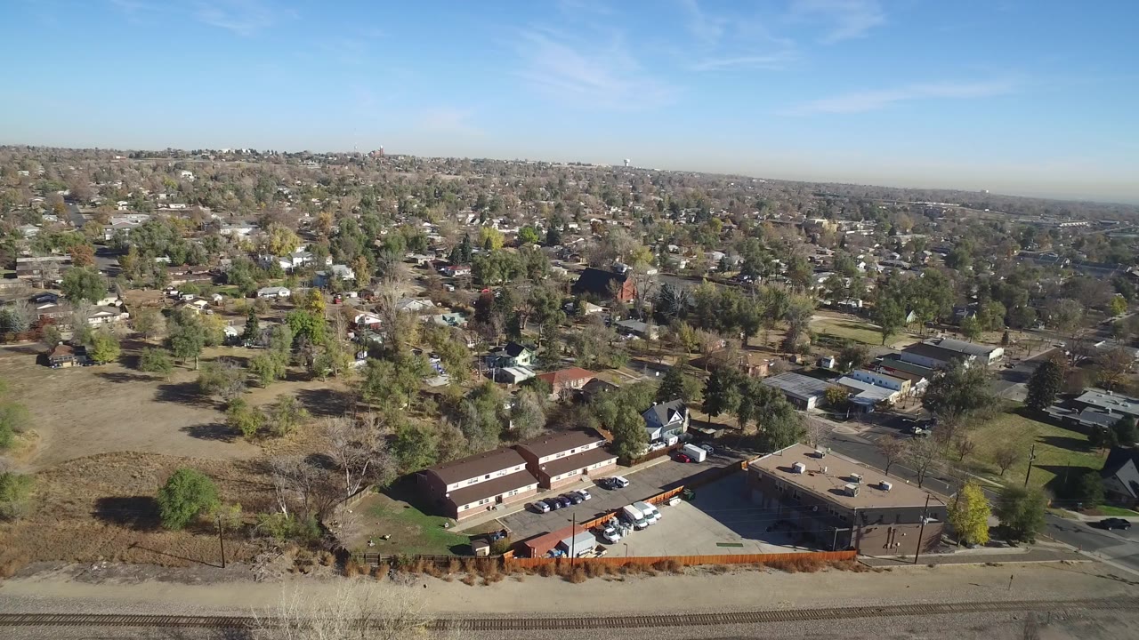 Opening aerial frame over Hidden Lake, Colorado showing low buildings, private homes, roads, trees, open brown grass, parked cars, and no visible people.