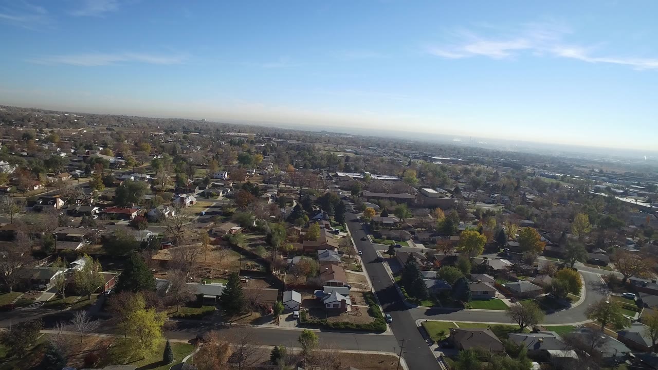 Aerial view over residential streets and homes under a blue sky.