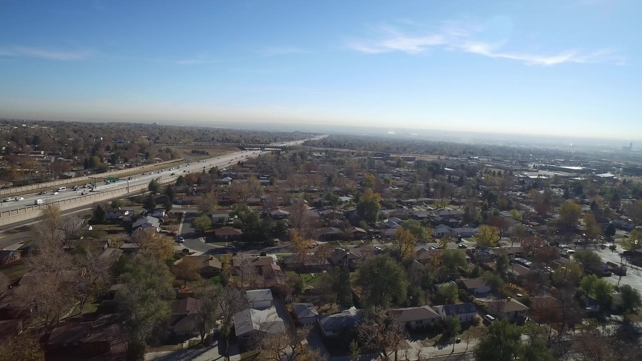 Aerial view of a highway beside suburban homes under a blue sky.