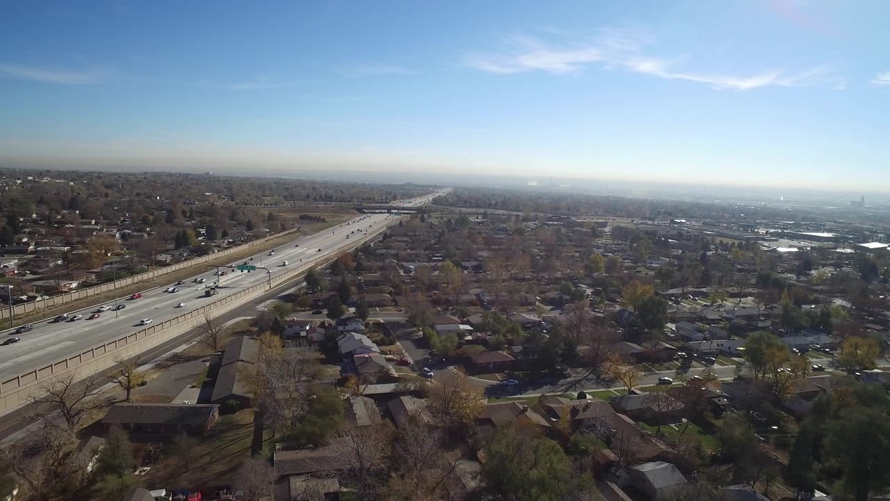 Aerial view of a divided highway through suburban homes under blue sky.