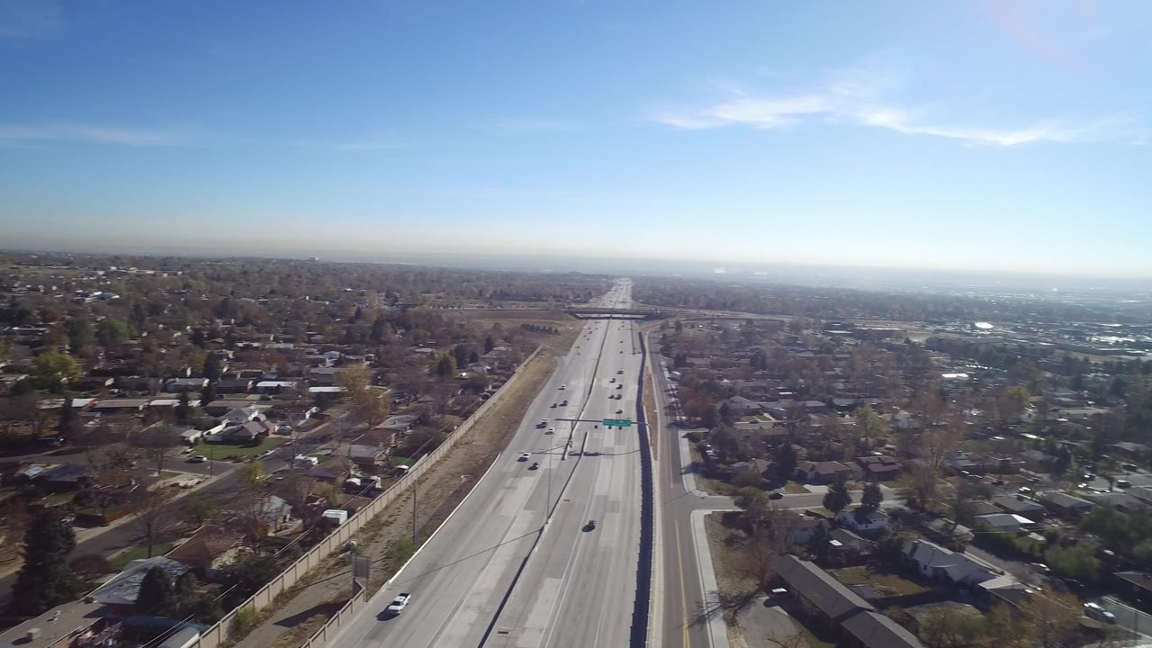 Aerial view of a highway beside residential neighborhoods under blue sky.