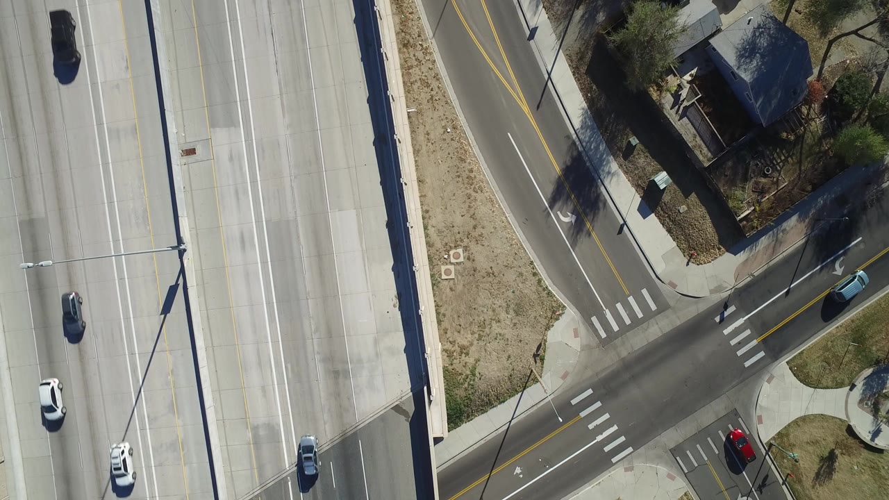 Overhead view of multi-lane road beside a residential side street and houses.