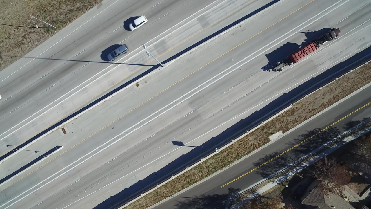 Overhead view of cars and a red trailer truck on a divided road.