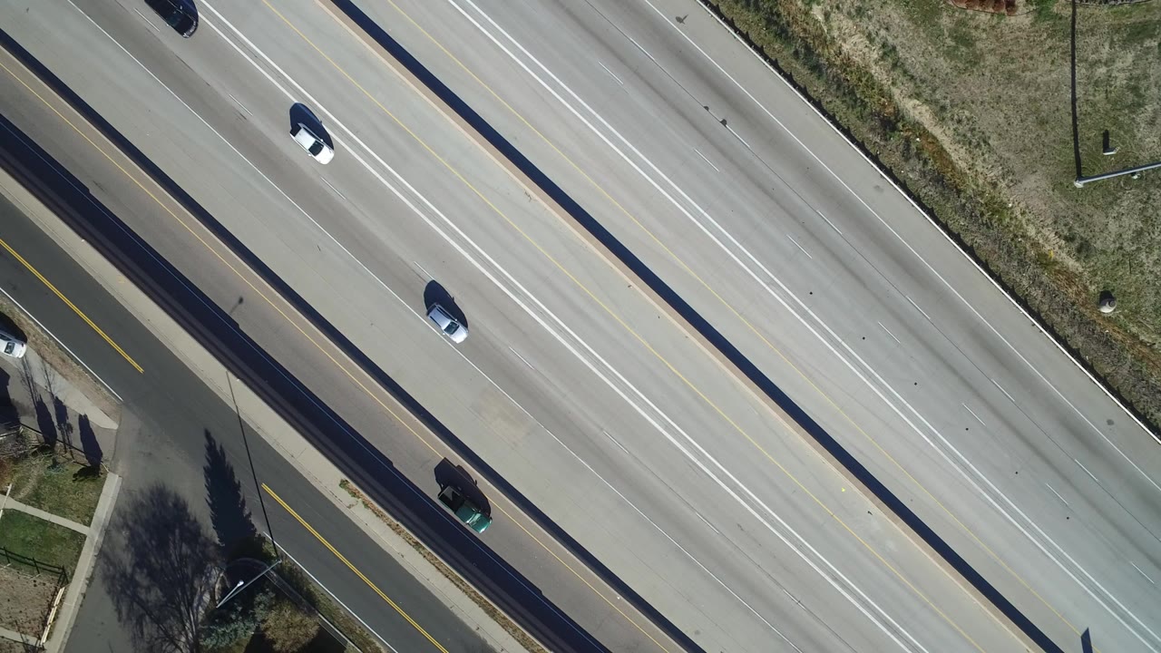 Overhead view of cars on a multi-lane highway beside a side road.
