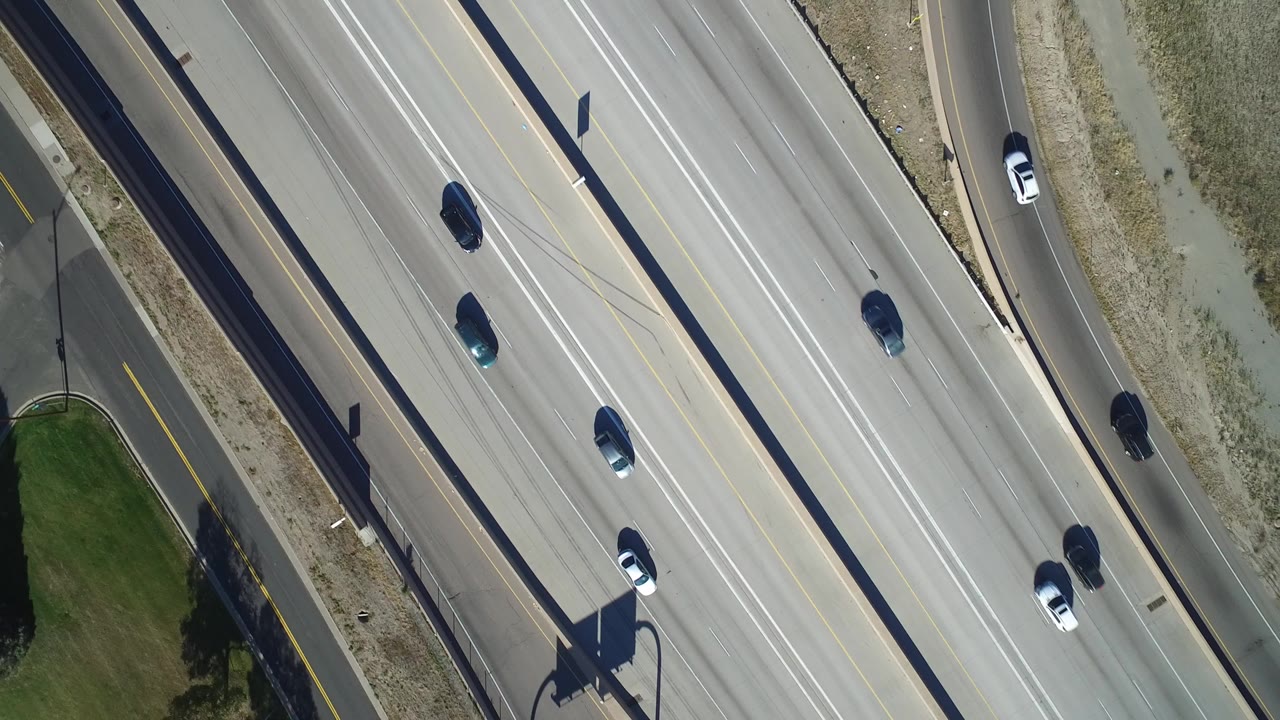 Overhead view of cars on a divided highway beside an access road.