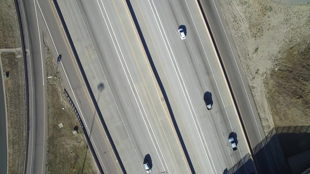 Overhead view of cars on a multilane highway beside dry grass