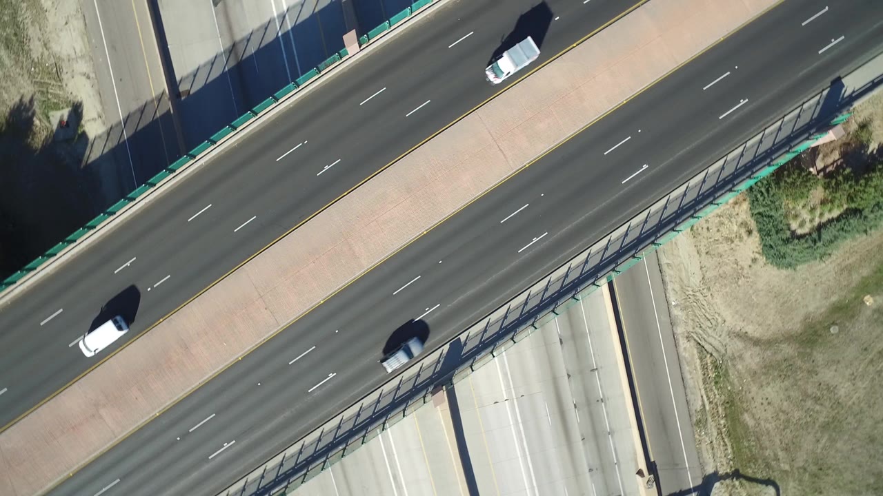 Overhead highway interchange with cars, overpass, and dry grass verge.