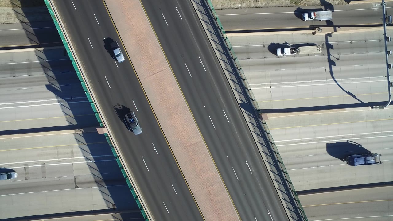 Overhead view of multilane highway traffic and an overpass.