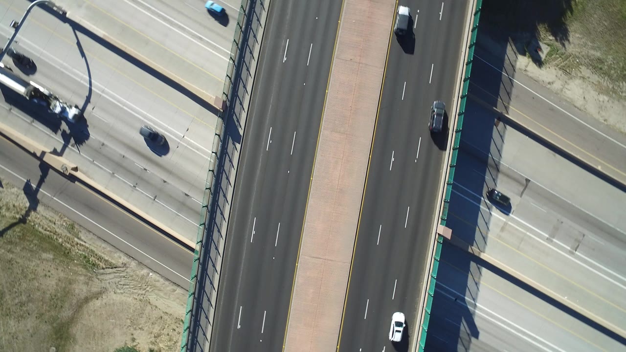 Overhead view of an overpass crossing a multi-lane highway with cars below.