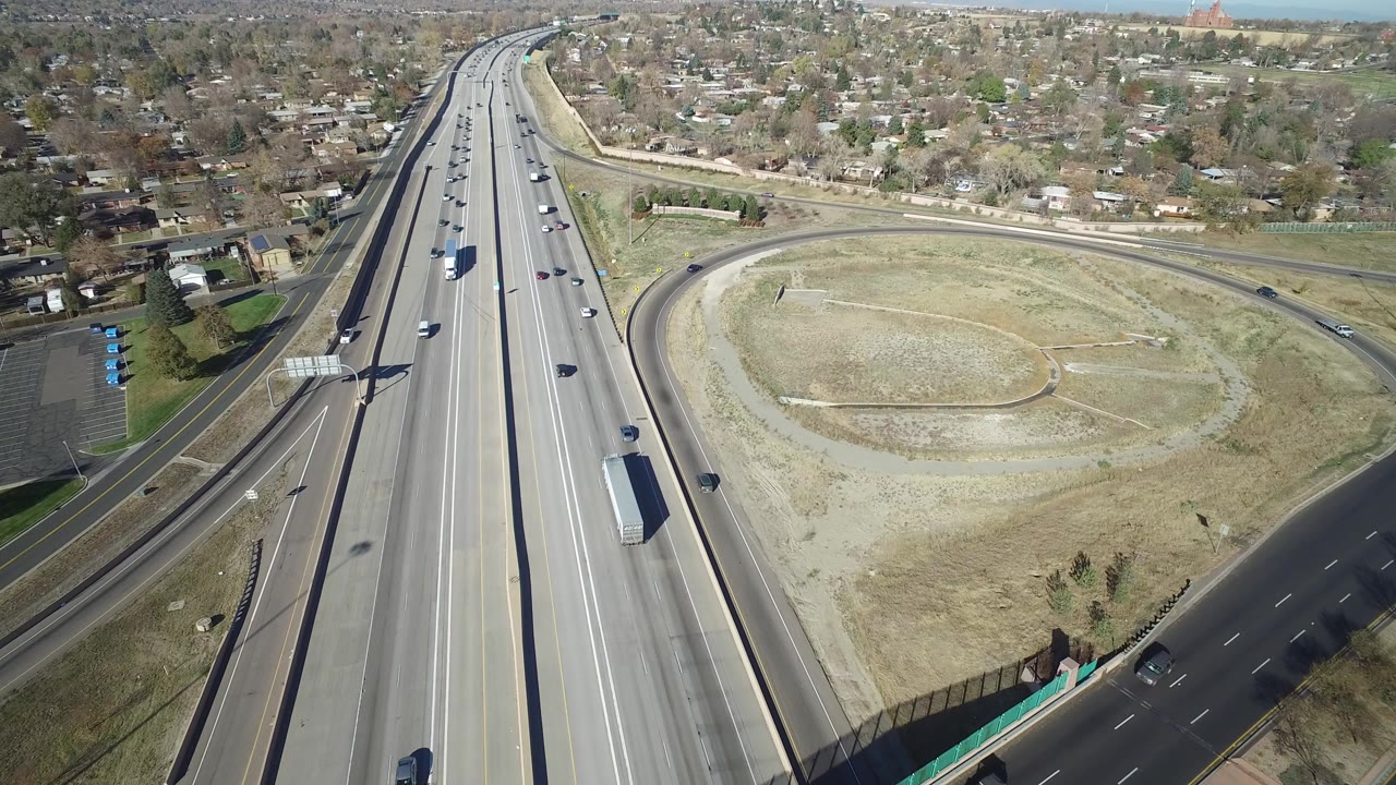 Aerial view of freeway lanes beside a curving overpass and residential homes.