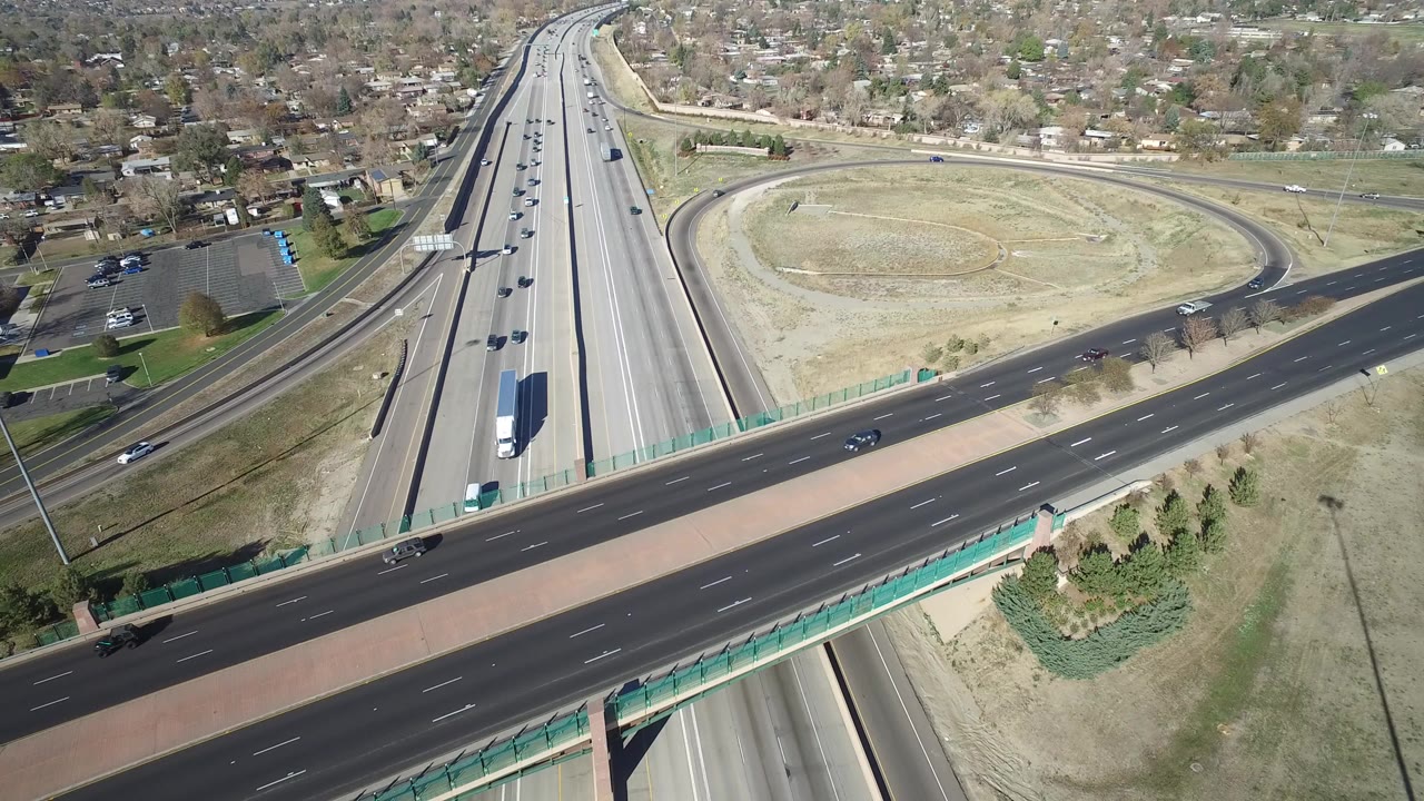 Aerial view of highway lanes passing under an overpass near suburban homes.