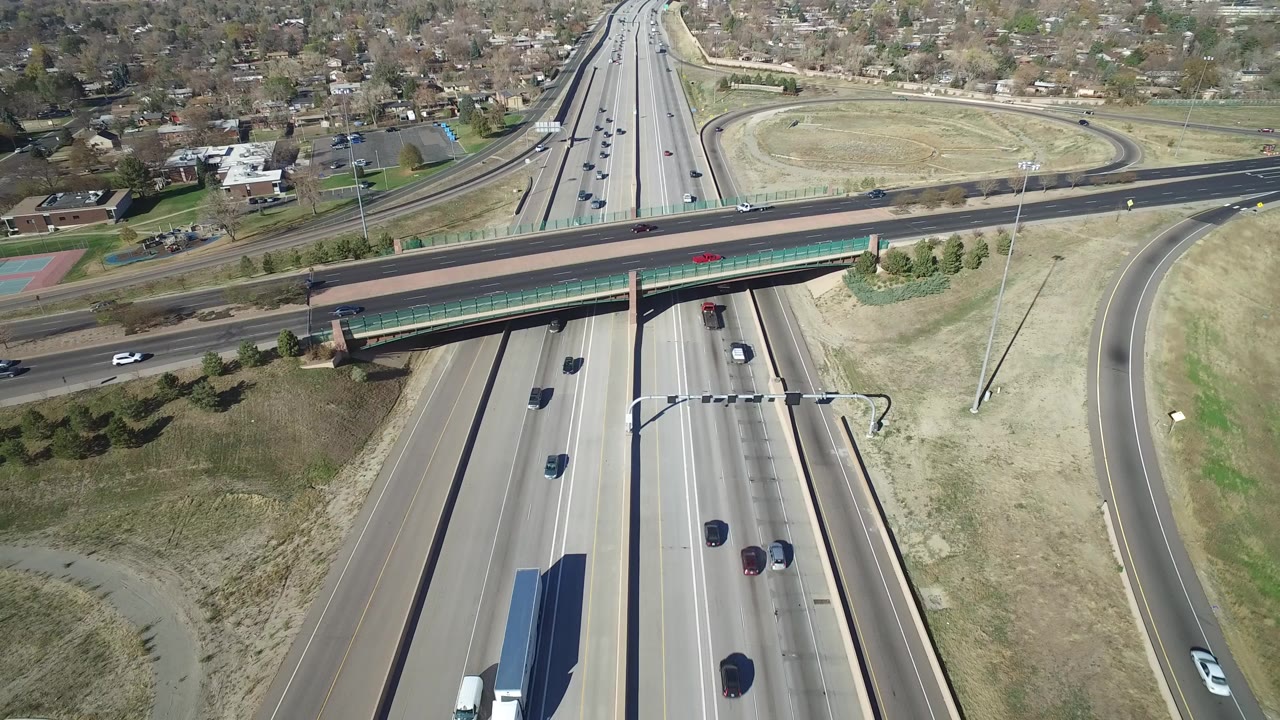Aerial view of a highway under an overpass with moving cars and ramps.